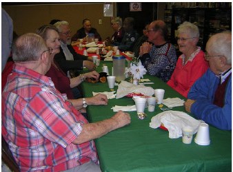 Members chatting over coffee at the green tables